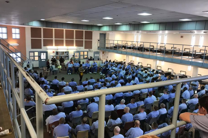 large group of males inmates watching a speaker